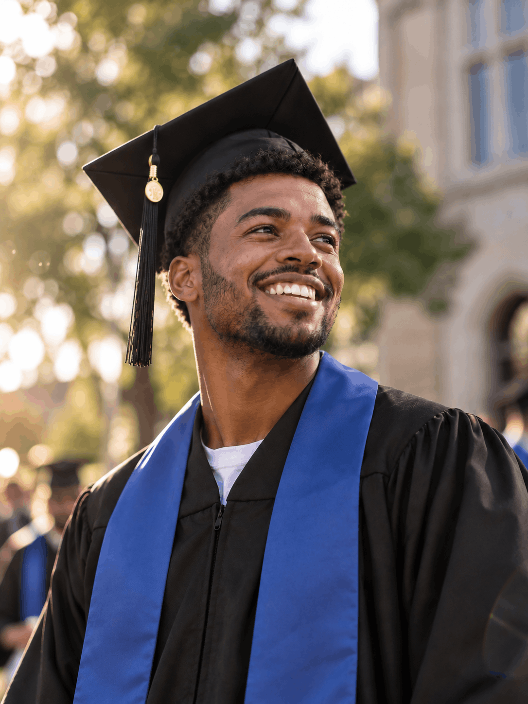 A college graduate in cap and gown smiling outdoors